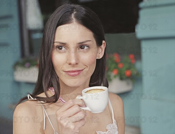 Hispanic woman drinking coffee at outdoor cafe