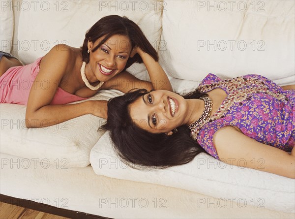 Multi-ethnic women laying on sofa