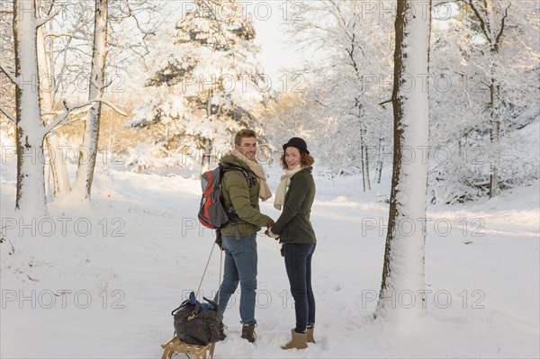 Caucasian couple pulling sled in snow