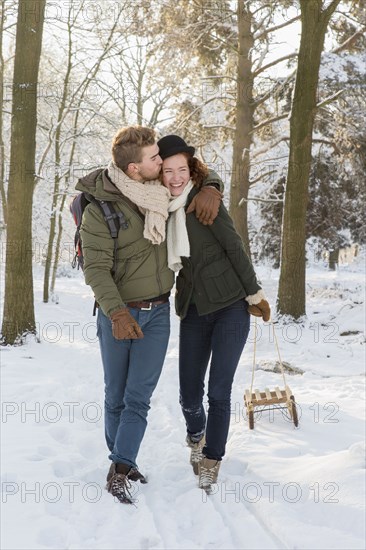 Caucasian couple pulling sled in snow