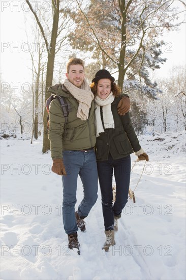 Caucasian couple pulling sled in snow