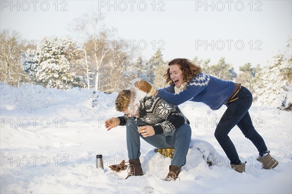 Caucasian couple playing in snow