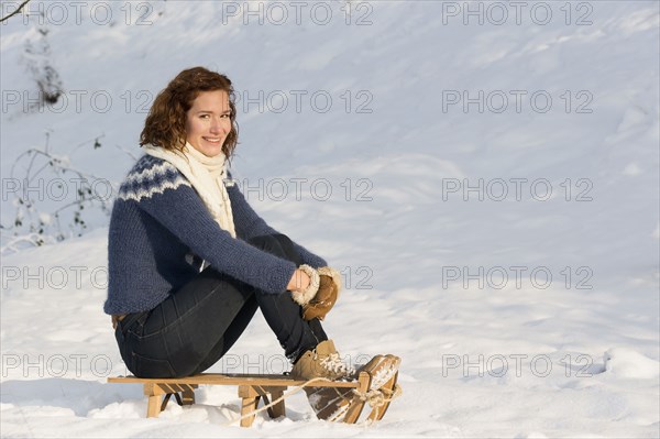 Caucasian woman sitting on sled in snow