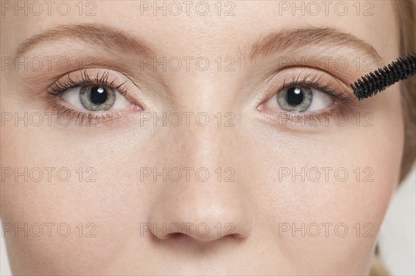 Caucasian woman applying mascara