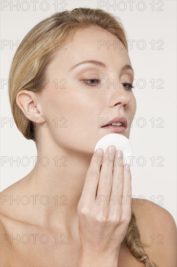 Nude Caucasian woman applying makeup