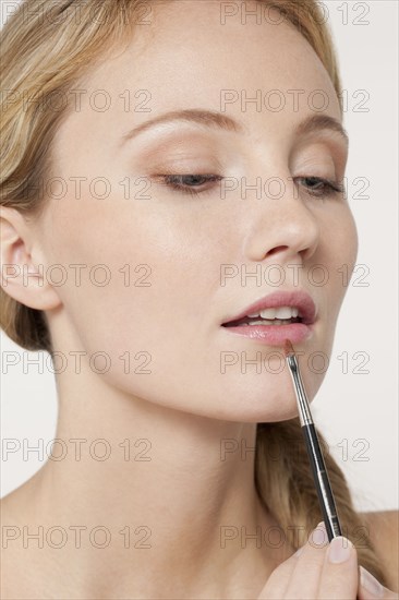 Caucasian woman applying makeup