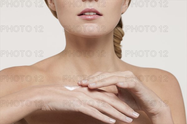 Nude Caucasian woman applying moisturizer