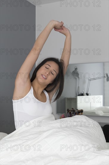 Mixed race woman stretching in bed