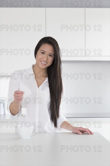 Mixed race woman having cup of tea in kitchen