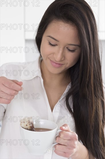Mixed race woman having cup of tea in kitchen