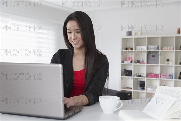 Mixed race businesswoman using laptop