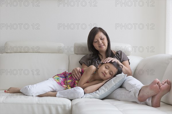 Asian mother and daughter relaxing on sofa