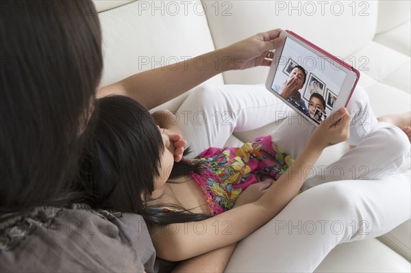 Asian mother and daughter talking to family on digital tablet
