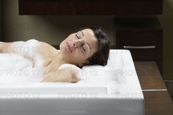 Caucasian woman relaxing in bubble bath