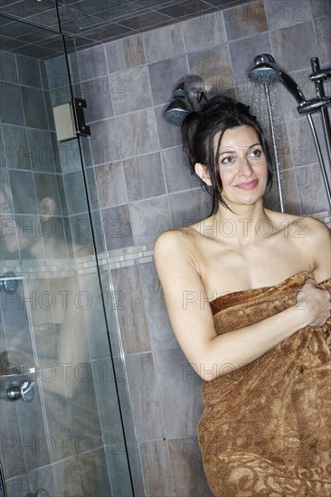 Caucasian woman wrapped in towel in shower