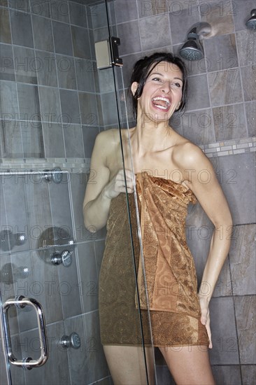 Caucasian woman wrapped in towel in shower