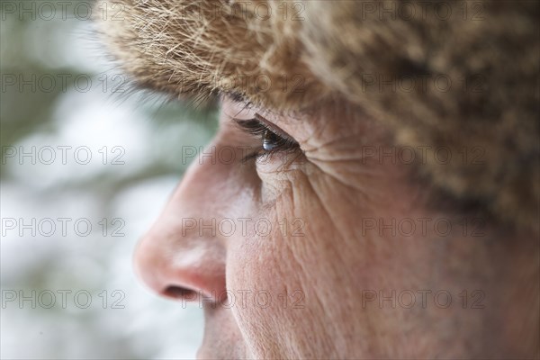 Close up of Caucasian man wearing furry hat in snow