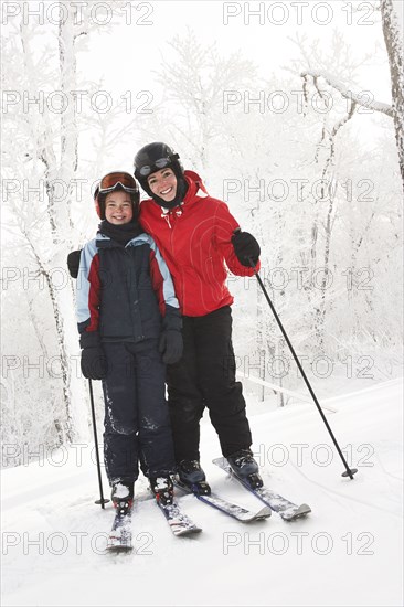 Caucasian mother and daughter cross country skiing in snow