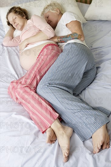 Caucasian pregnant lesbian couple laying on bed