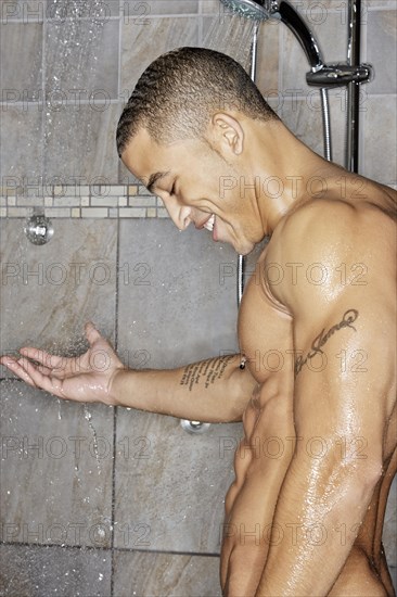 Mixed race man showering in bathroom