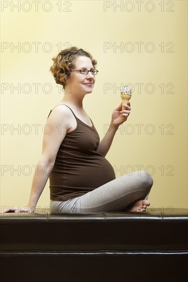 Caucasian pregnant woman eating ice cream cone