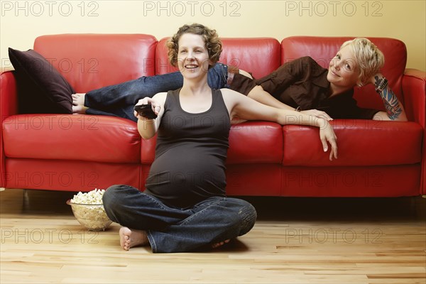 Caucasian pregnant lesbian couple watching TV