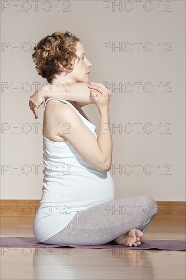 Caucasian pregnant woman stretching on yoga mat