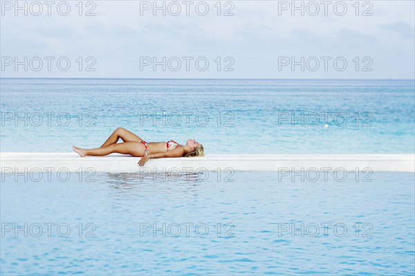 Caucasian woman laying by infinity pool