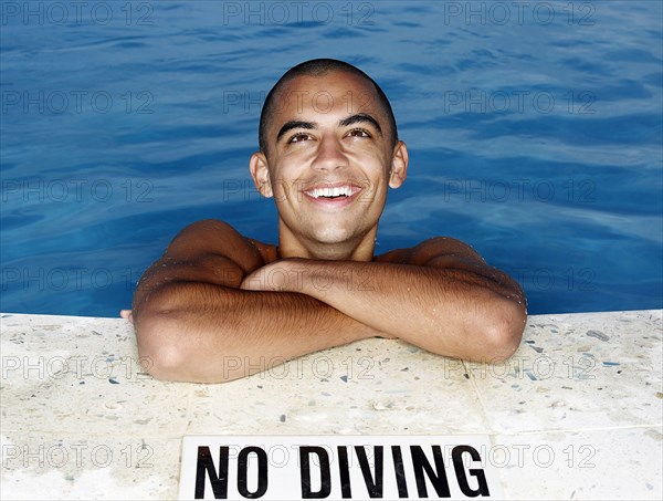Mixed race man smiling at edge of swimming pool