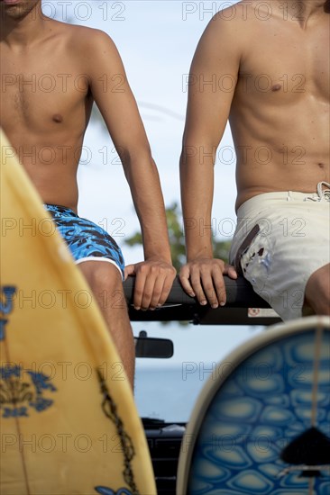 Surfers sitting in 4x4 with surfboards