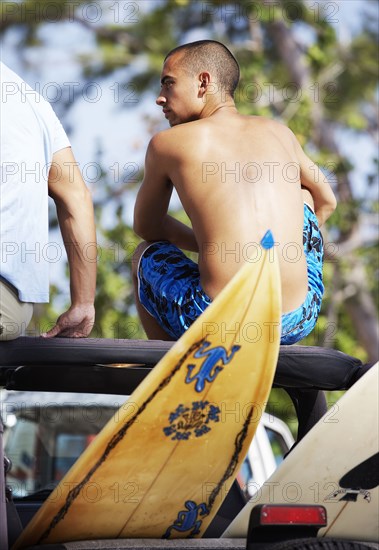 Surfers sitting in 4x4 on beach