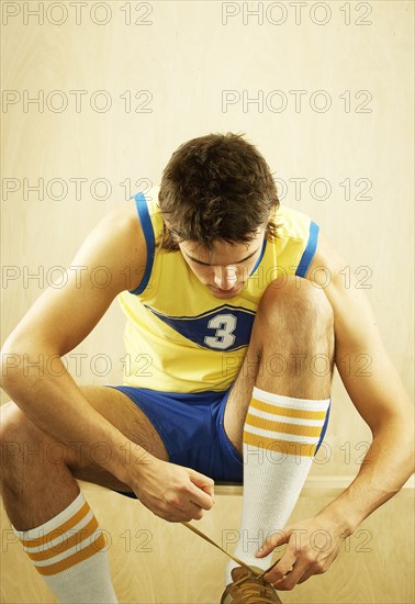 Caucasian basketball player tying shoes