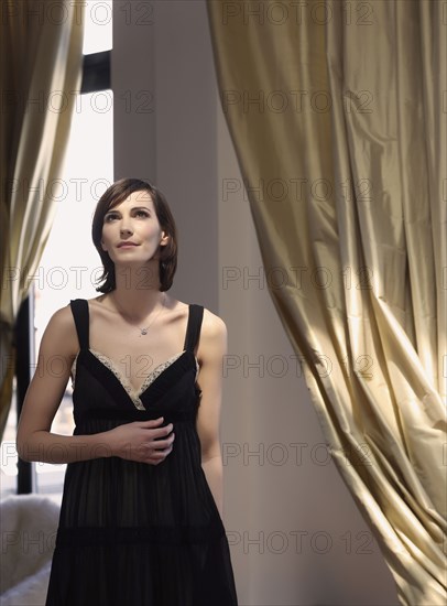 Caucasian woman standing under gold curtains