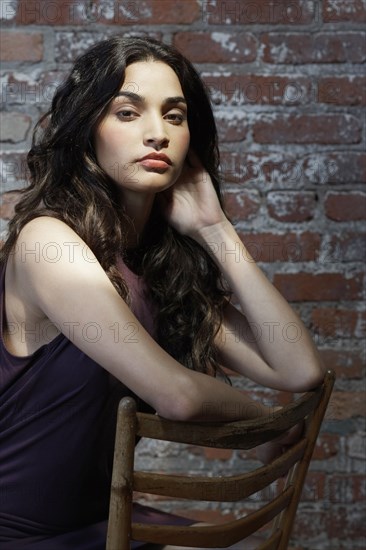 Hispanic woman sitting in wooden chair