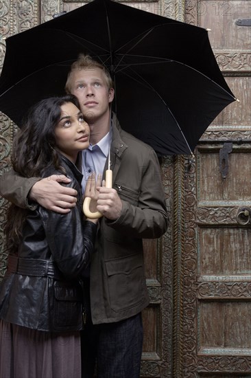 Couple under umbrella at ornate door