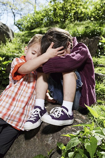 Mixed race boy comforting sister in park