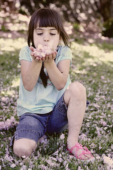 Mixed race girl playing with flowers in park