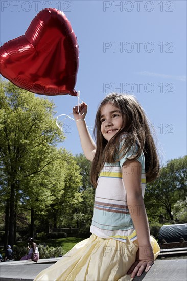 Caucasian girl holding heart-shape balloon
