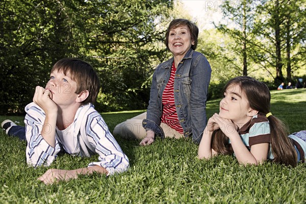 Senior Caucasian woman and grandchildren sitting in park