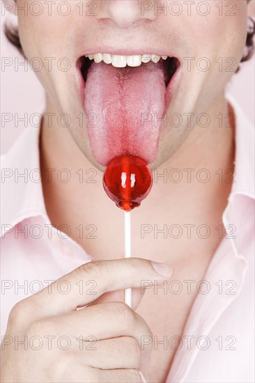 Caucasian man licking lollipop