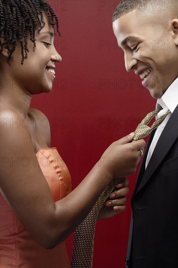 Woman in dress adjusting man's tie