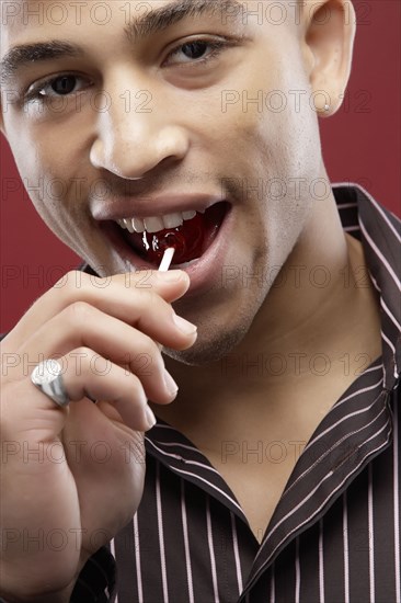 Mixed race man eating lollipop