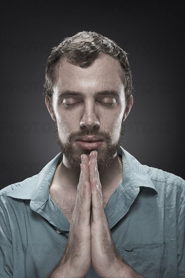 Serious man praying with eyes closed