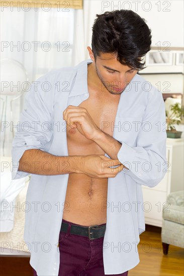 Mixed race teenager buttoning shirt cuffs