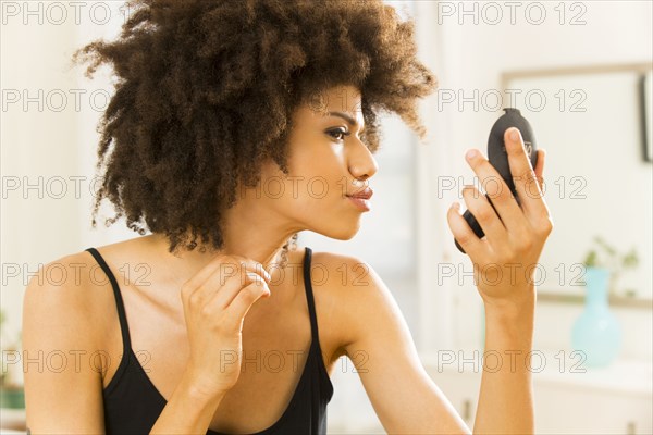 Mixed race woman checking her makeup