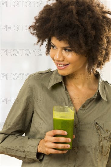 Mixed race woman drinking green smoothie
