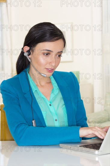 Mixed race businesswoman wearing headset and using laptop