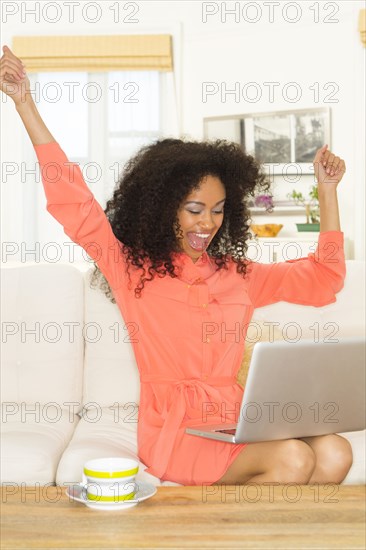 Mixed race woman cheering at laptop