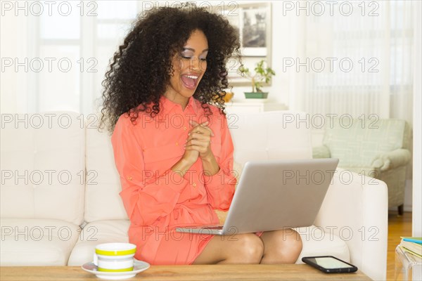 Mixed race woman cheering at laptop