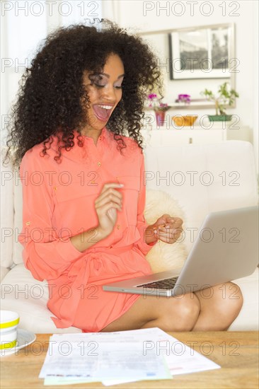 Mixed race woman cheering at laptop